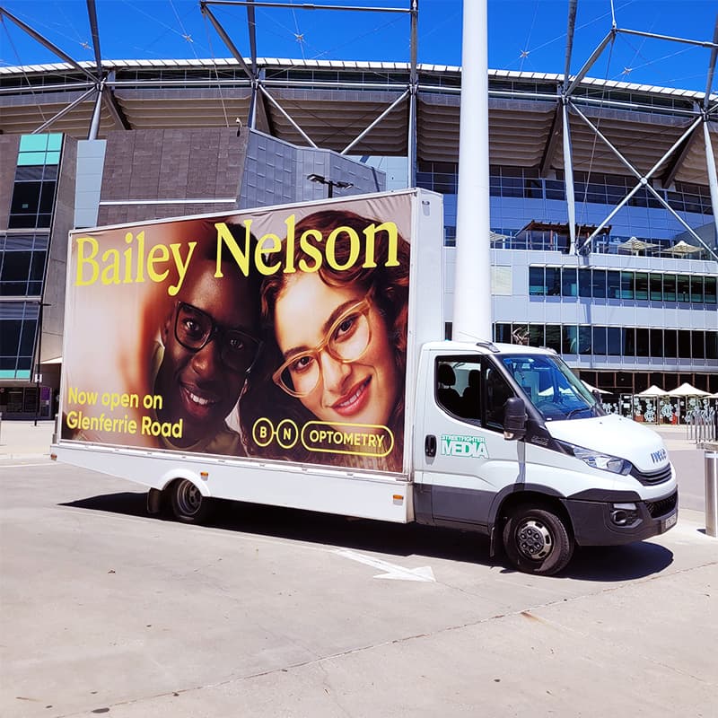 Mobile billboard truck with large side display faces parked outside a stadium